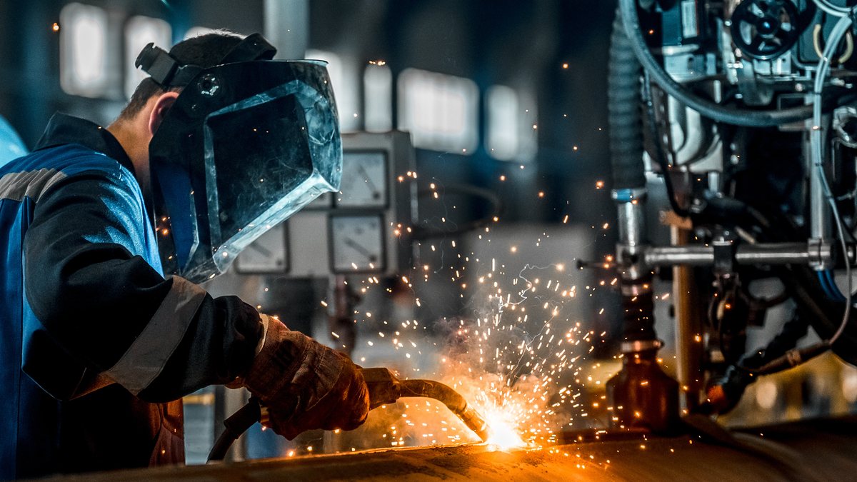 Welder repairing commercial equipment in the shop