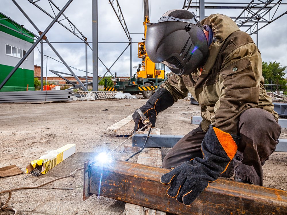 Welder repairing heavy machinery on site